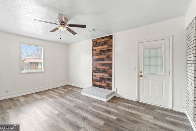 foyer with visible vents, ceiling fan, a textured ceiling, and wood finished floors