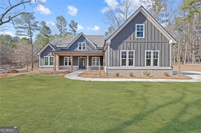 modern farmhouse style home with brick siding, board and batten siding, a front yard, a standing seam roof, and metal roof