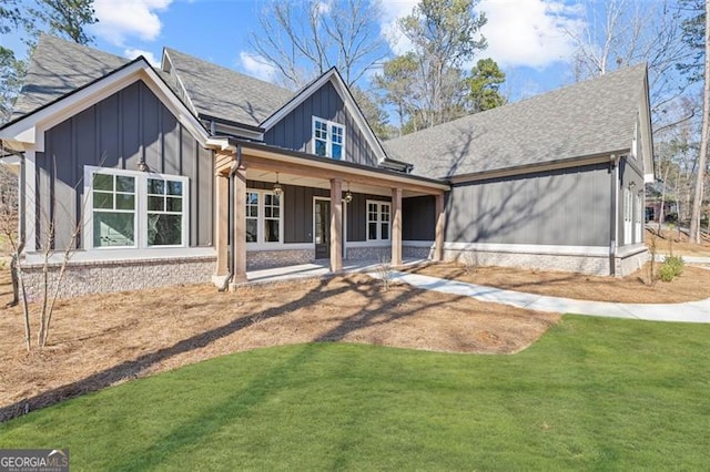 view of front facade featuring board and batten siding, brick siding, a shingled roof, and a front lawn