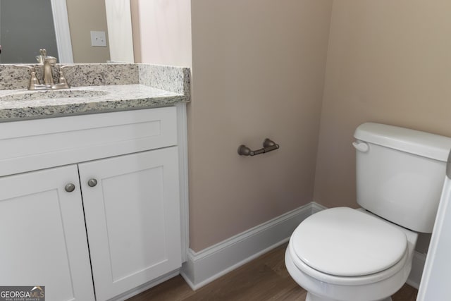 bathroom with toilet, baseboards, wood finished floors, and vanity