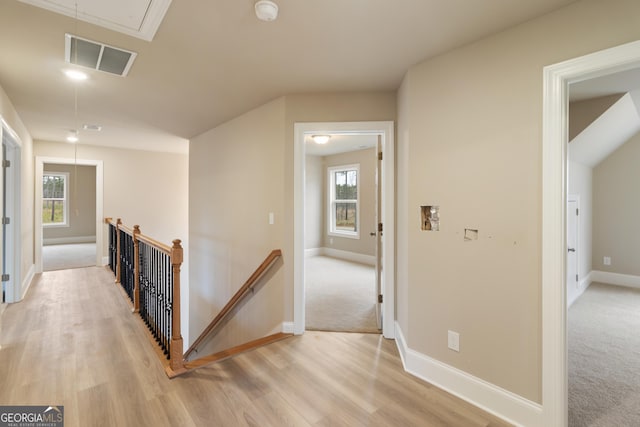 hall featuring light colored carpet, visible vents, baseboards, an upstairs landing, and attic access