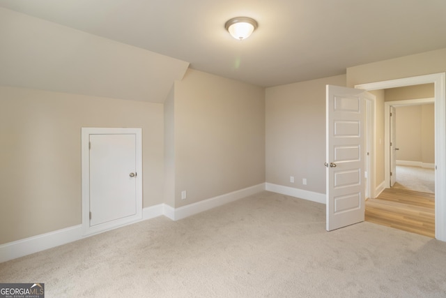 additional living space with light carpet and baseboards