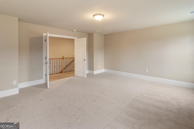 empty room with visible vents, baseboards, and light colored carpet