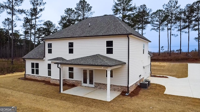 exterior space featuring french doors, brick siding, a patio, roof with shingles, and cooling unit