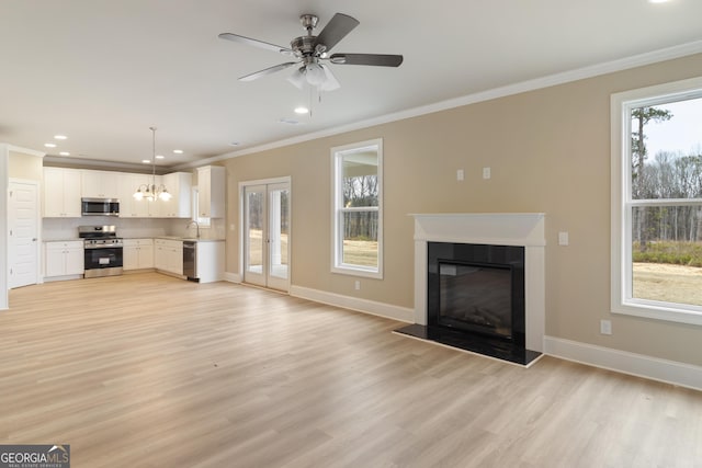 unfurnished living room featuring light wood-type flooring, baseboards, crown molding, and a sink