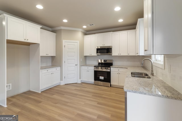 kitchen with stainless steel appliances, light wood-type flooring, white cabinets, and a sink