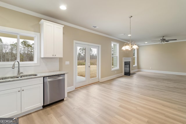 kitchen featuring crown molding, visible vents, stainless steel dishwasher, a glass covered fireplace, and a sink