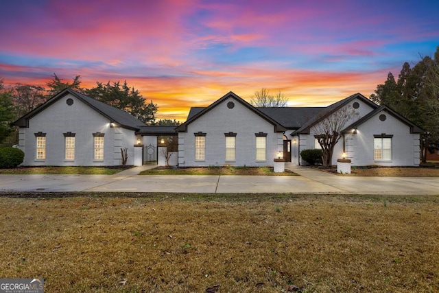 view of front of home with brick siding, concrete driveway, and a yard