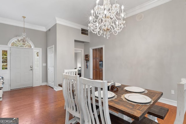 dining area with an inviting chandelier, visible vents, wood finished floors, and ornamental molding