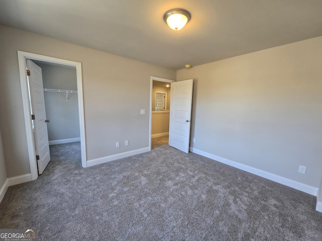 unfurnished bedroom featuring a walk in closet, a closet, carpet flooring, and baseboards