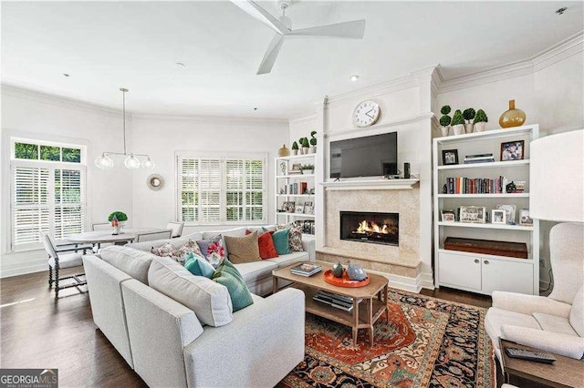 living area featuring a ceiling fan, dark wood-type flooring, crown molding, and a high end fireplace