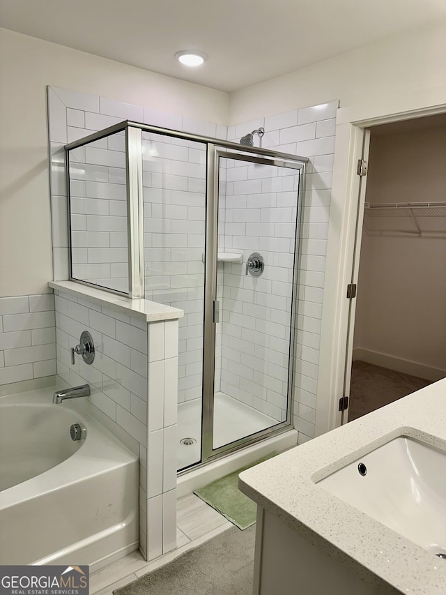 full bath with a garden tub, a spacious closet, a shower stall, and vanity