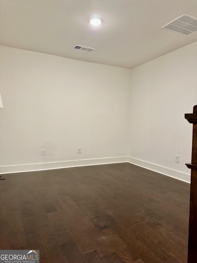 unfurnished room featuring dark wood-style floors, visible vents, and baseboards