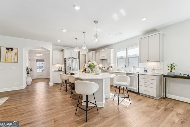 kitchen featuring arched walkways, appliances with stainless steel finishes, a kitchen bar, and a sink