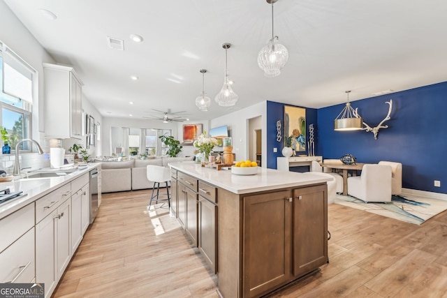 kitchen featuring visible vents, light wood-style floors, open floor plan, a sink, and plenty of natural light