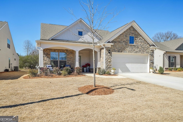 view of front facade with stone siding, covered porch, driveway, and central AC unit