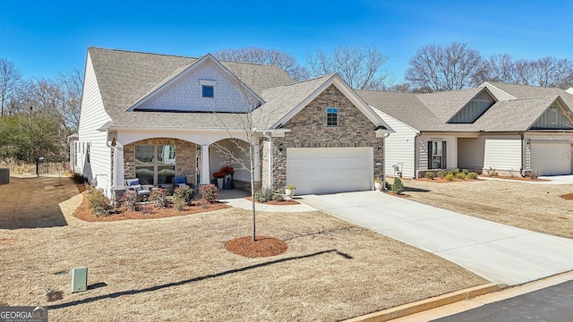 view of front facade featuring stone siding, a shingled roof, covered porch, and concrete driveway