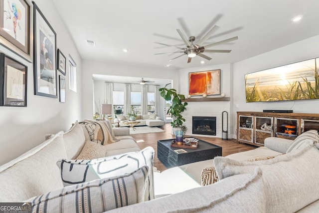 living room with recessed lighting, visible vents, a fireplace, and wood finished floors