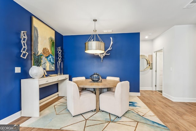 dining area featuring wood finished floors, visible vents, and baseboards