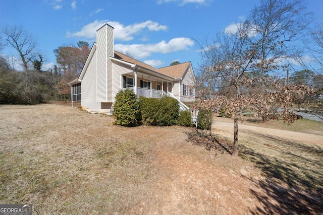 view of side of property featuring covered porch and a chimney