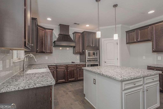 kitchen with dark wood-style flooring, custom exhaust hood, appliances with stainless steel finishes, a sink, and dark brown cabinets