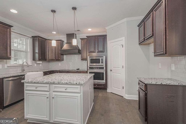 kitchen featuring appliances with stainless steel finishes, premium range hood, a sink, and dark brown cabinets