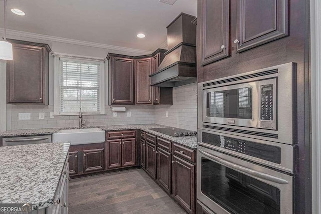 kitchen featuring ornamental molding, a sink, stainless steel appliances, premium range hood, and backsplash