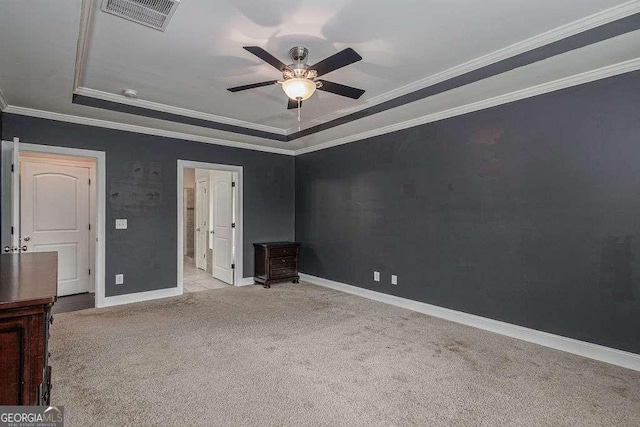 unfurnished bedroom featuring carpet floors, a tray ceiling, visible vents, ornamental molding, and baseboards