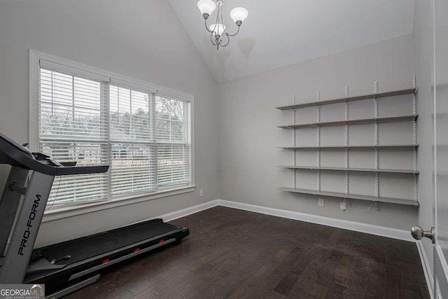 workout room featuring vaulted ceiling, dark wood-type flooring, an inviting chandelier, and baseboards