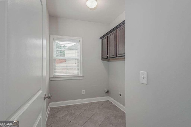 laundry area featuring cabinet space, light tile patterned floors, baseboards, and electric dryer hookup