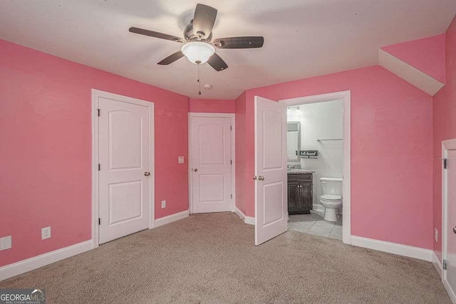 unfurnished bedroom featuring baseboards, ceiling fan, ensuite bath, and light colored carpet