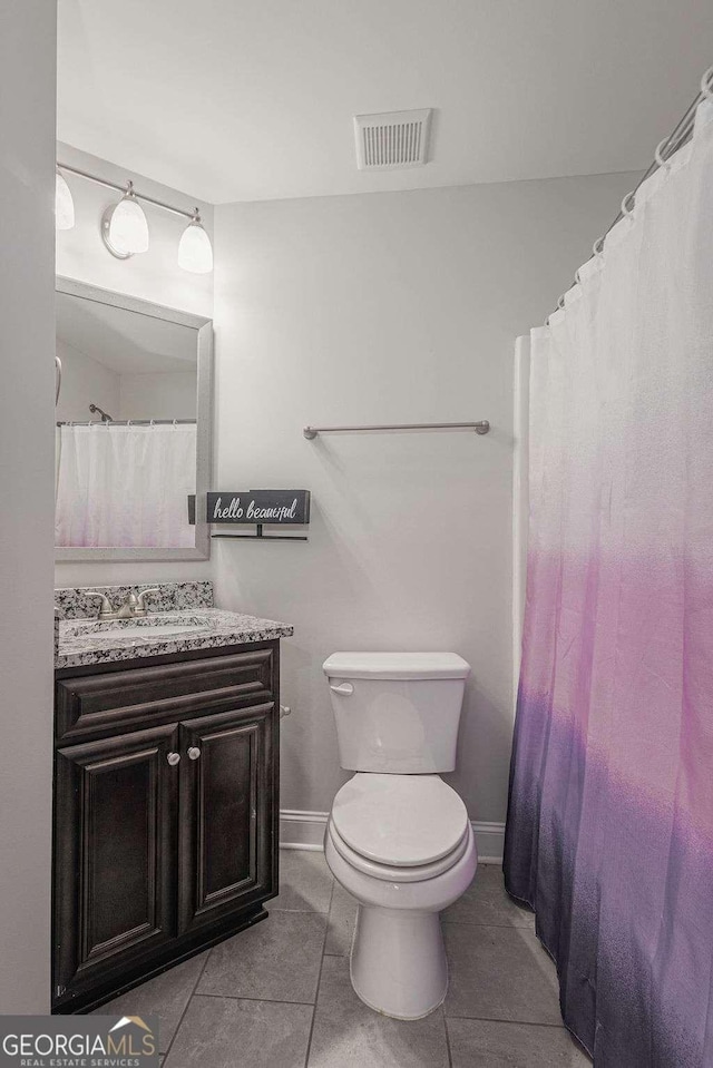 bathroom with toilet, vanity, baseboards, visible vents, and tile patterned floors