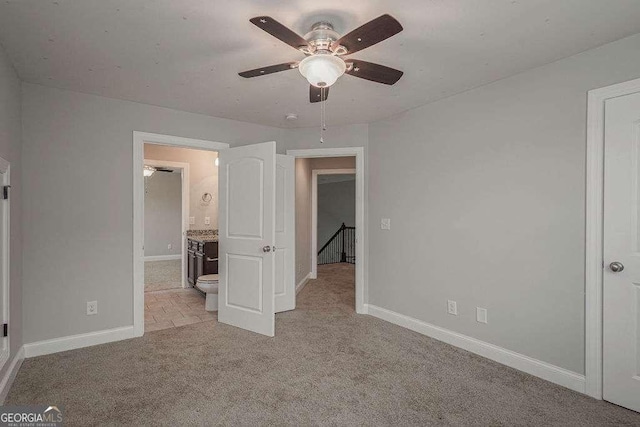 unfurnished bedroom with light carpet, ceiling fan, baseboards, and ensuite bathroom