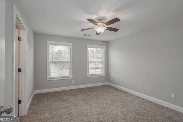 spare room with carpet floors, visible vents, and baseboards