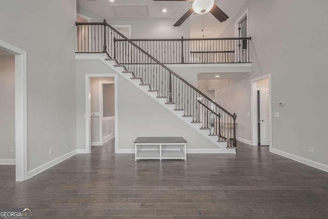 interior space featuring a high ceiling, wood finished floors, a ceiling fan, and baseboards