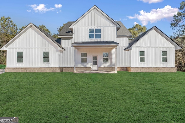 back of property with a shingled roof, a lawn, and board and batten siding