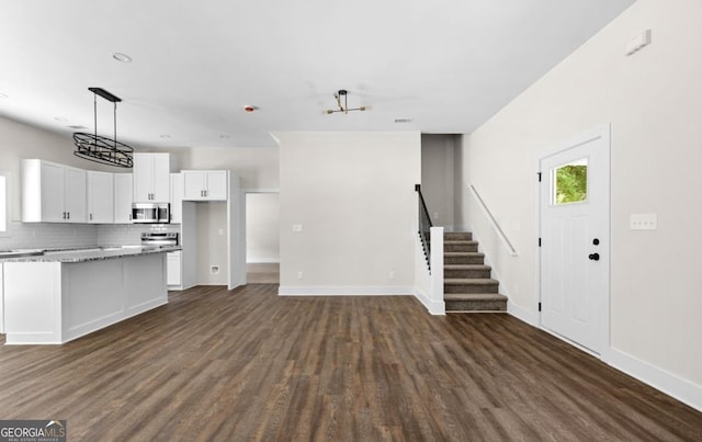 kitchen with dark wood-style floors, white cabinets, stainless steel microwave, and backsplash