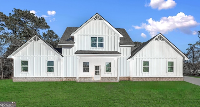 back of house with a lawn, board and batten siding, and roof with shingles