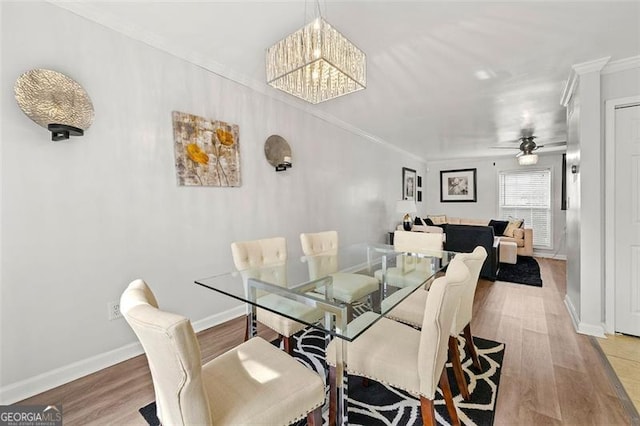 dining area with ornamental molding, baseboards, light wood finished floors, and ceiling fan with notable chandelier