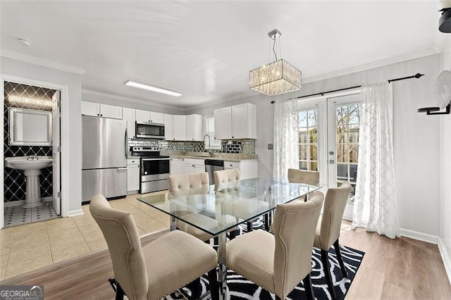 dining space with light wood-type flooring, baseboards, ornamental molding, and french doors