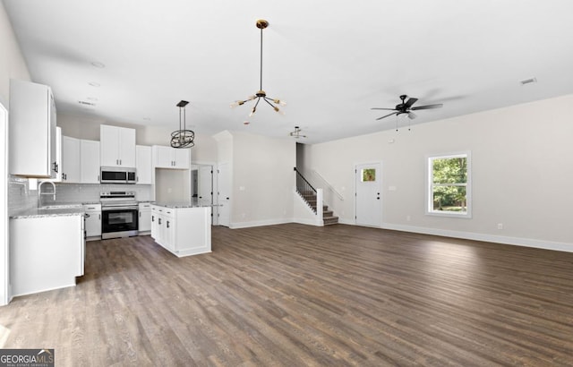 kitchen with open floor plan, stainless steel appliances, backsplash, and dark wood finished floors