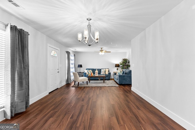 living area with an inviting chandelier, dark wood finished floors, visible vents, and baseboards