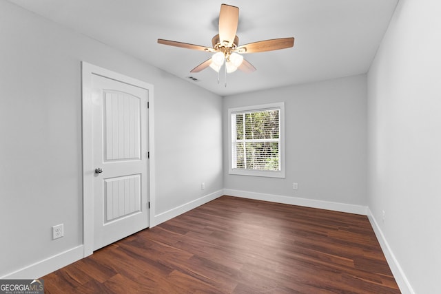 unfurnished room with a ceiling fan, visible vents, baseboards, and wood finished floors