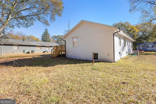 back of property with central AC, brick siding, and a lawn