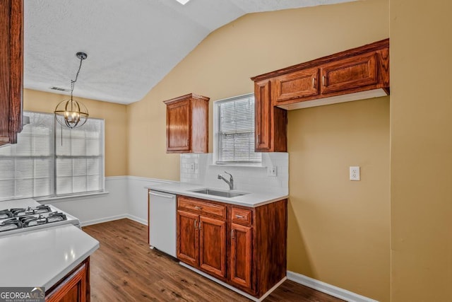 kitchen with dishwashing machine, dark wood-style floors, vaulted ceiling, pendant lighting, and a sink