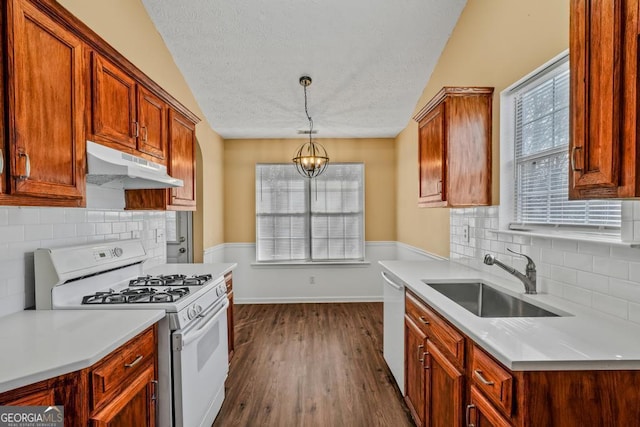 kitchen featuring dark wood-style flooring, light countertops, a sink, white appliances, and under cabinet range hood