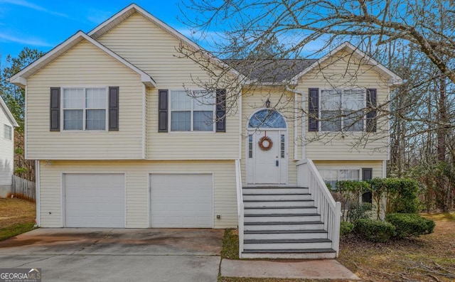 raised ranch featuring concrete driveway and an attached garage