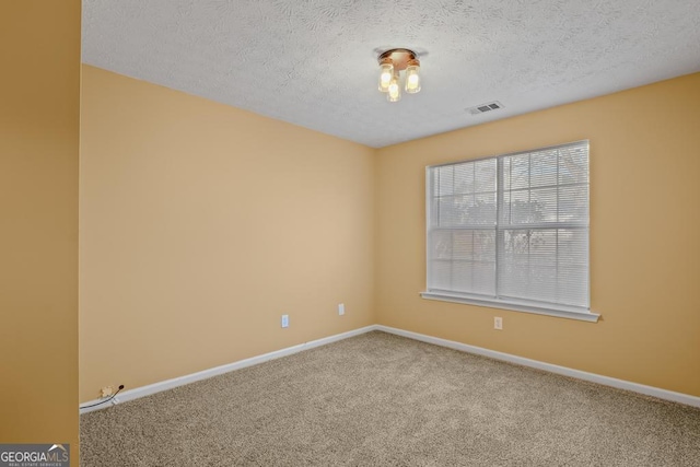 carpeted empty room featuring a textured ceiling, visible vents, and baseboards