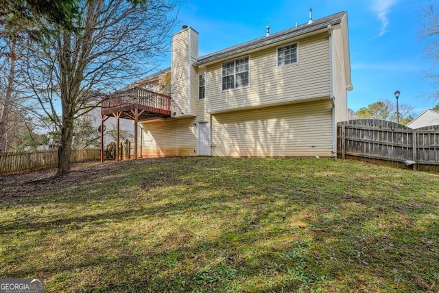 back of property with a deck, a yard, a chimney, and fence