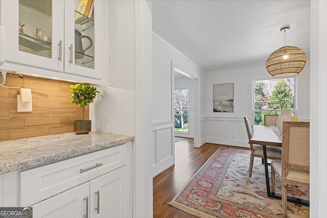 interior space featuring plenty of natural light, pendant lighting, crown molding, and dark wood-type flooring